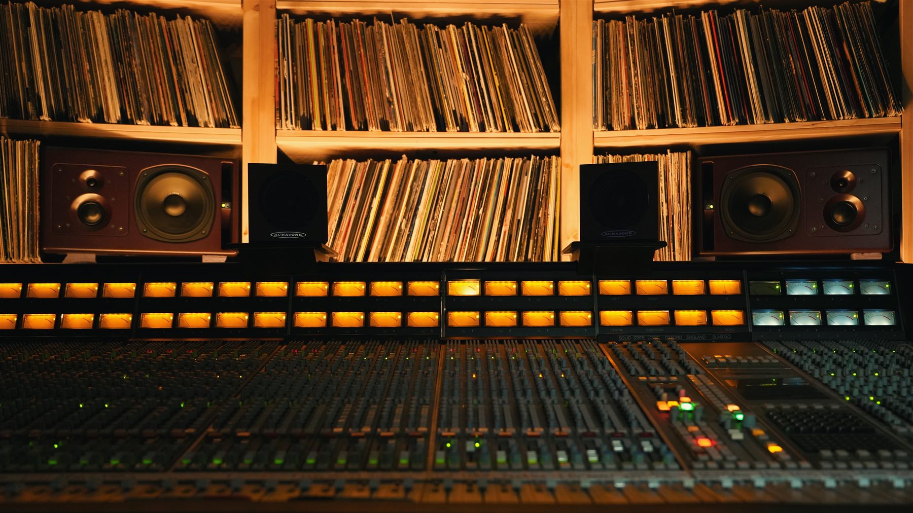 SSL mixing console beneath a wall of vinyl records