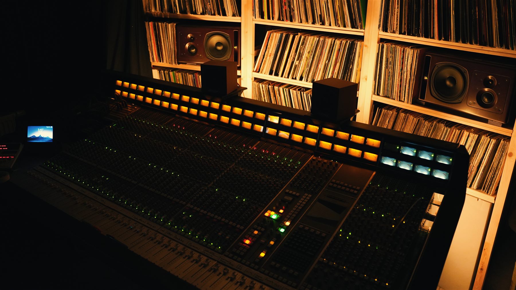 Mixing console with monitors and a wall of vinyl records