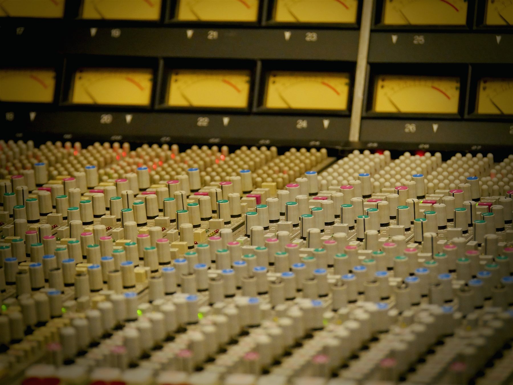 Close-up of vintage VU meters and colored console knobs