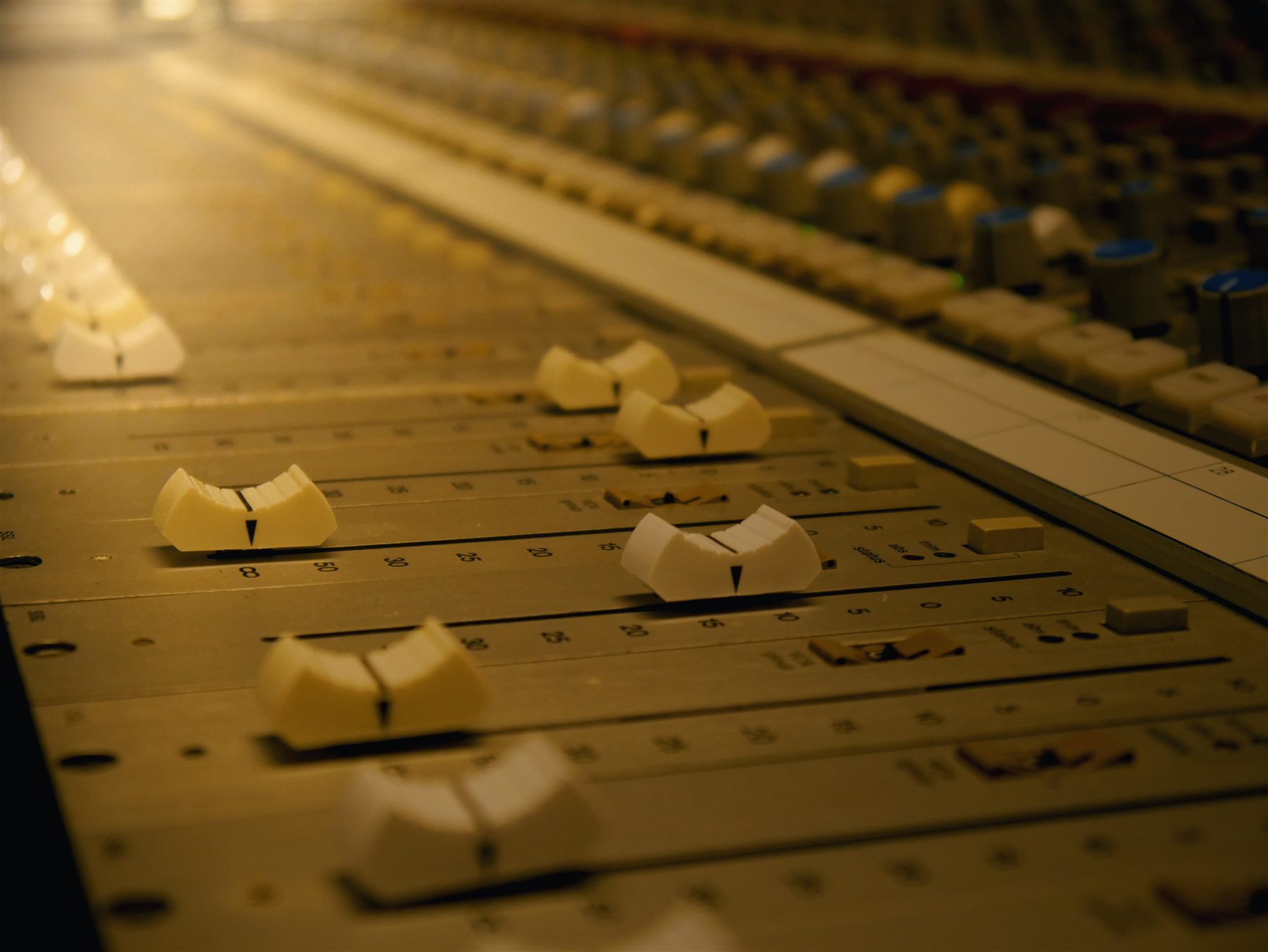 Close-up of console faders mid-mix